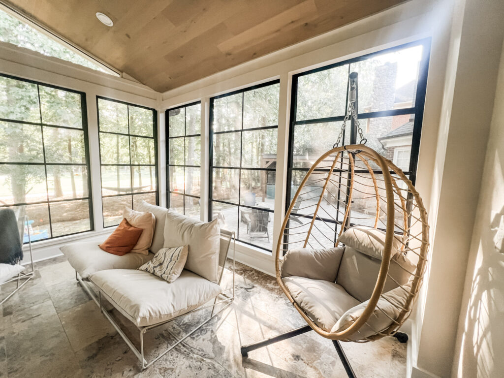conversation-friendly home design led this sun porch renovation with comfortable seating facing each other. a suspended egg chair is in the foreground