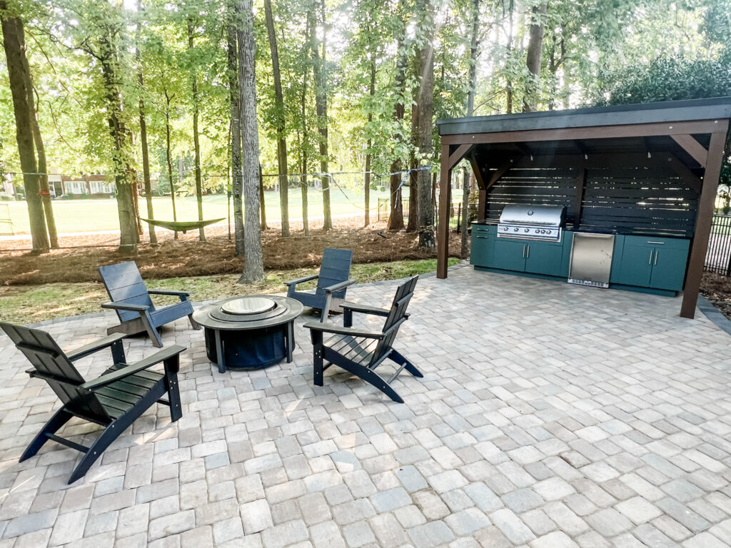 conversation-friendly home design renovated this outdoor patio. firepit is surrounded by dark Adirondack chairs in a circle