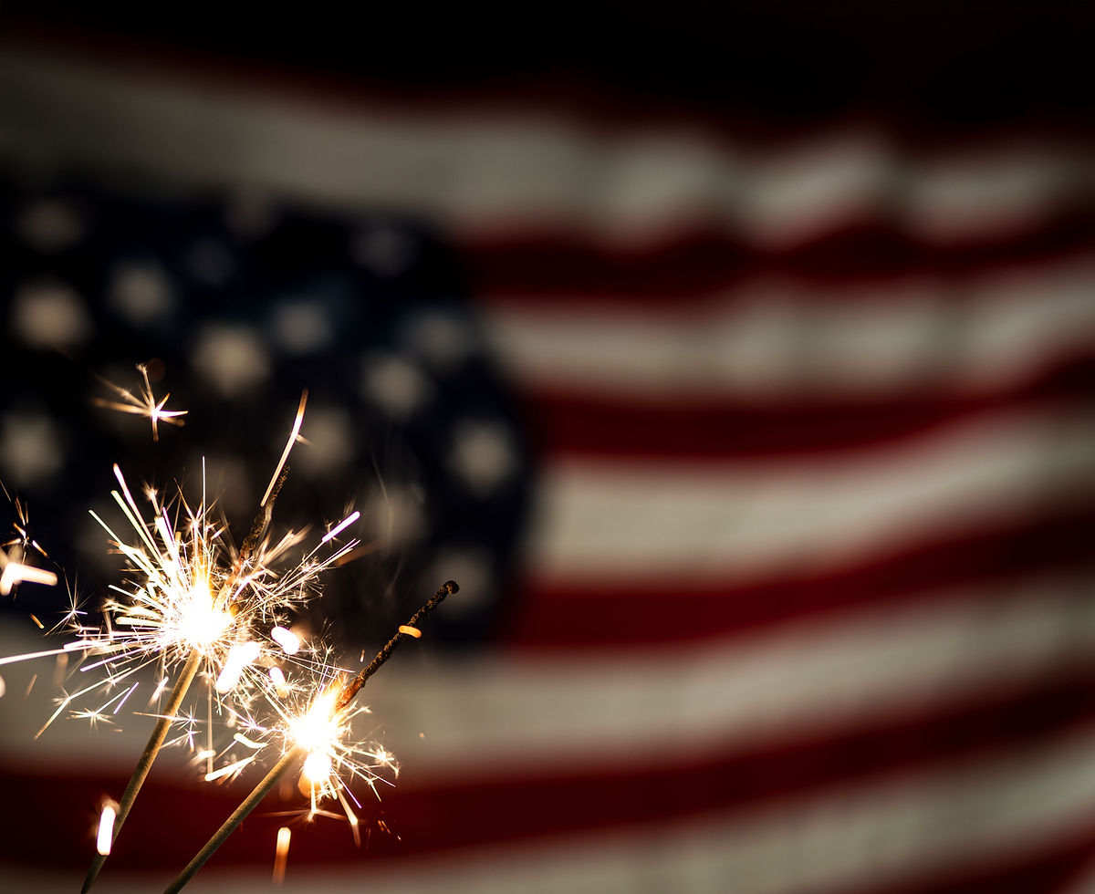 close up image of sparklers burning with an American flag in the background