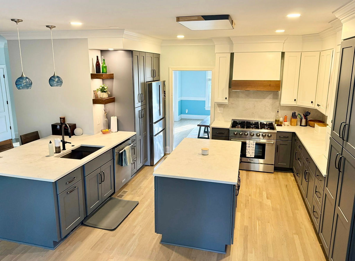 Modern kitchen with blue-gray cabinets, white countertops, light wood floor, and stainless steel appliances. Bright lighting, blue accents.