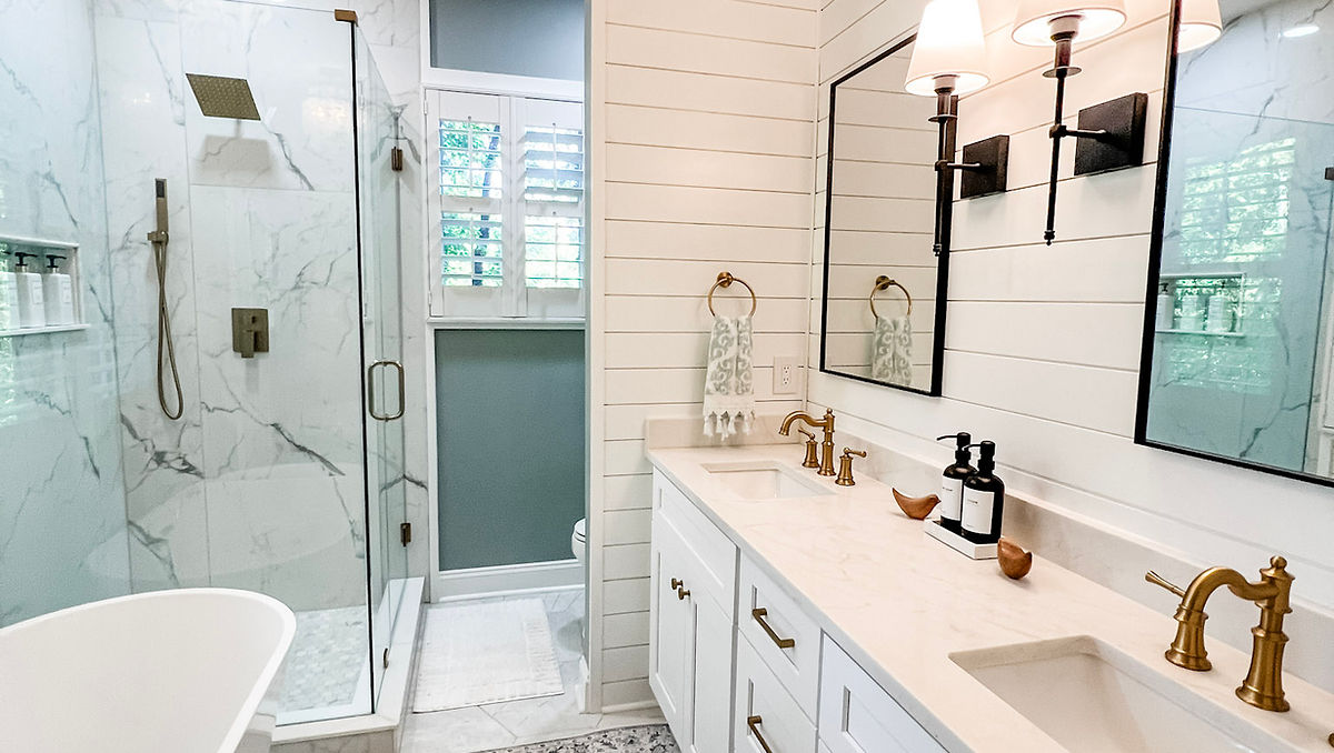 home renovation near Huntersville, NC featuring renovated bathroom with shiplap walls, bright white double vanity, and marble tiled shower in the background.