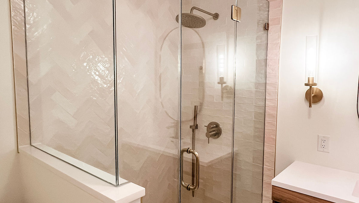 home renovation near Huntersville, NC featuring renovated bathroom with pink tiled shower, wooden vanity, and gold accents.