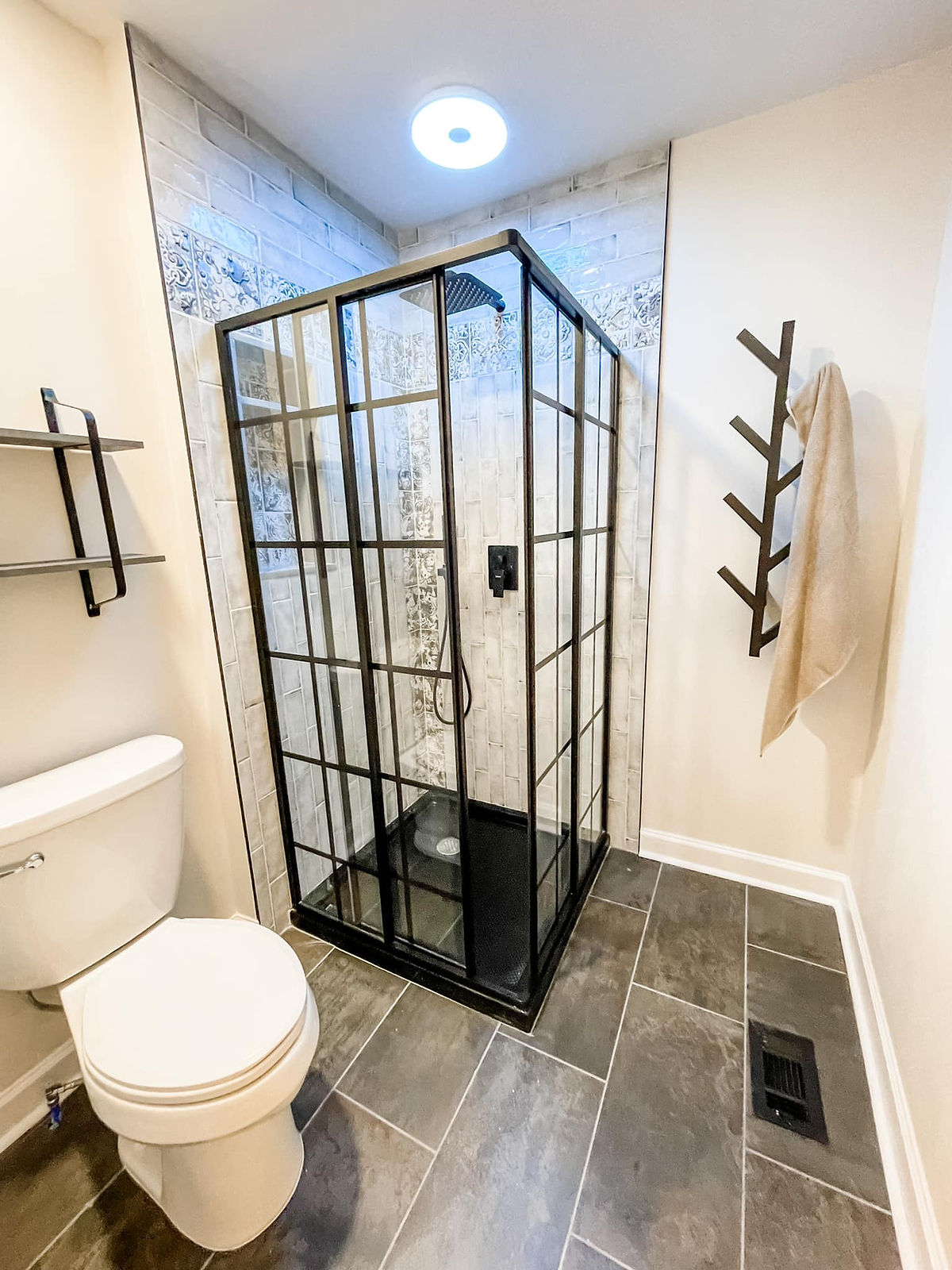 renovated bathroom with unique dark framedglass shower stall