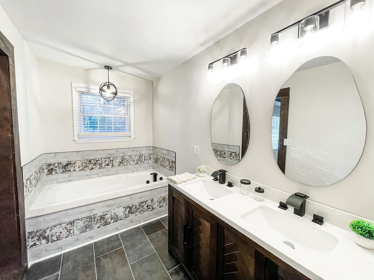 renovated bathroom with tile tub surround, dark gray tile flooring, and wooden vanity