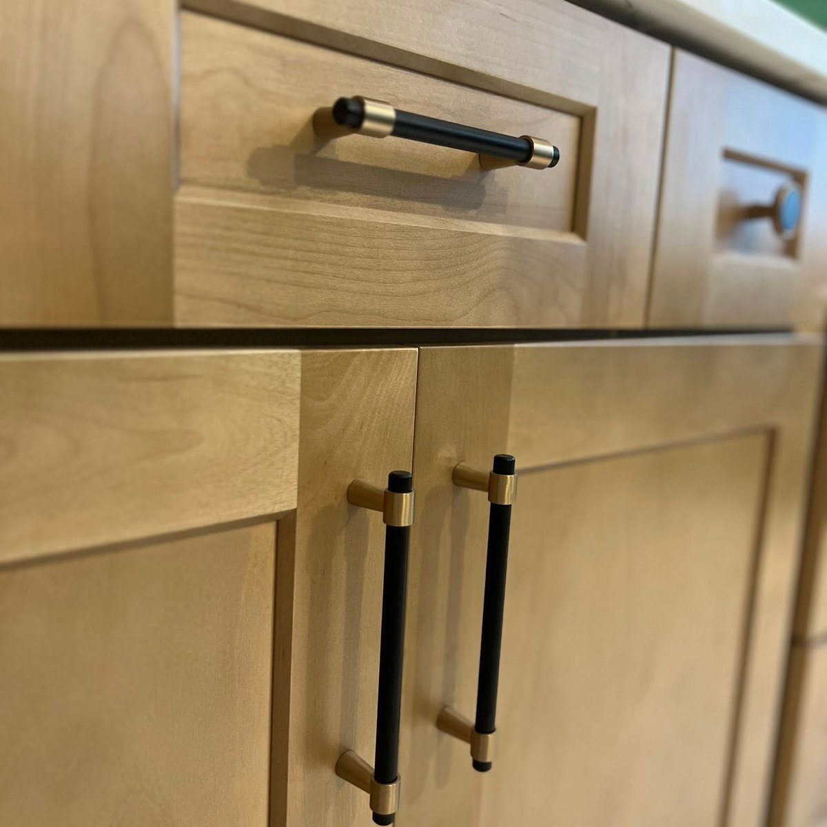 close up on light wood cabinetry with black and gold hardware