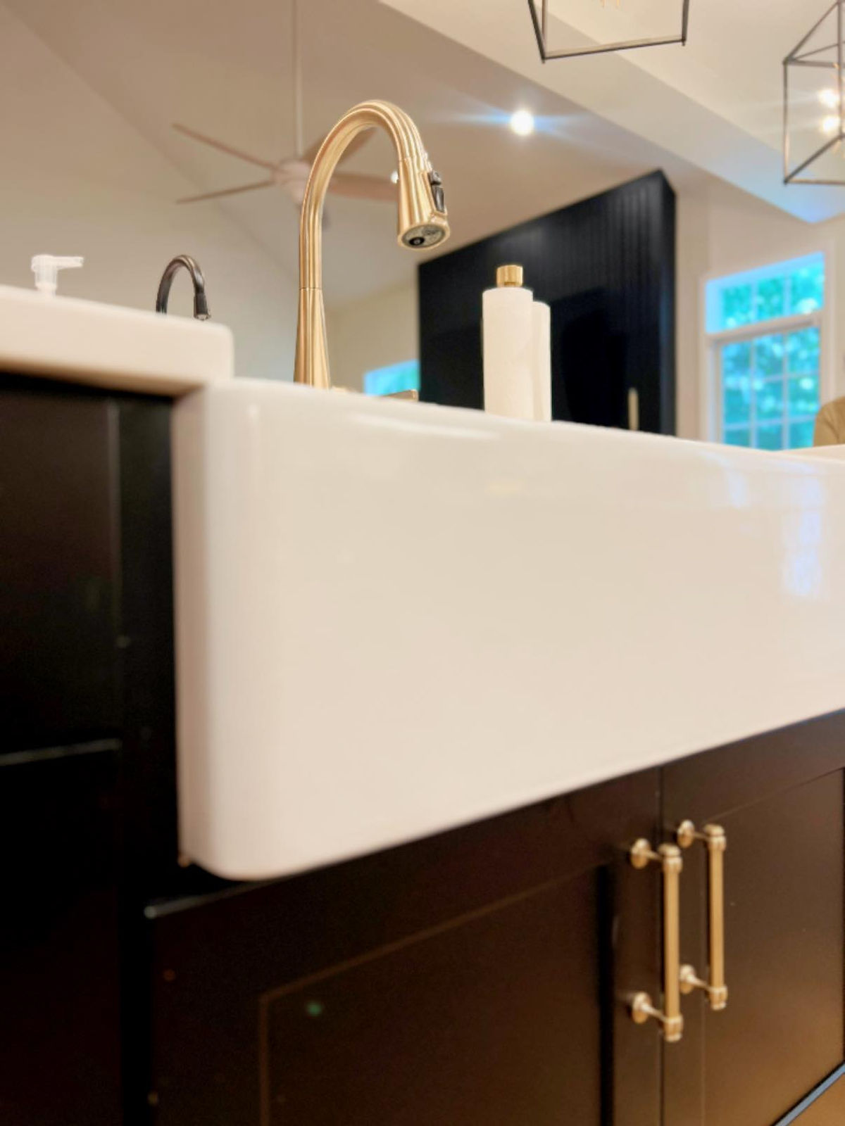 home renovation near Huntersville, NC featuring farmhouse sink in black cabinetry with gold faucets and handles