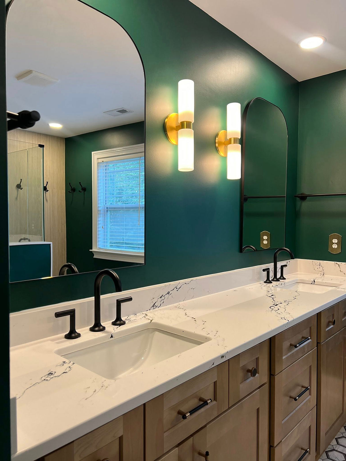 home renovation near Davidson, NC featuring renovated bathroom painted green with light wood double vanity and arched mirrors with black frames