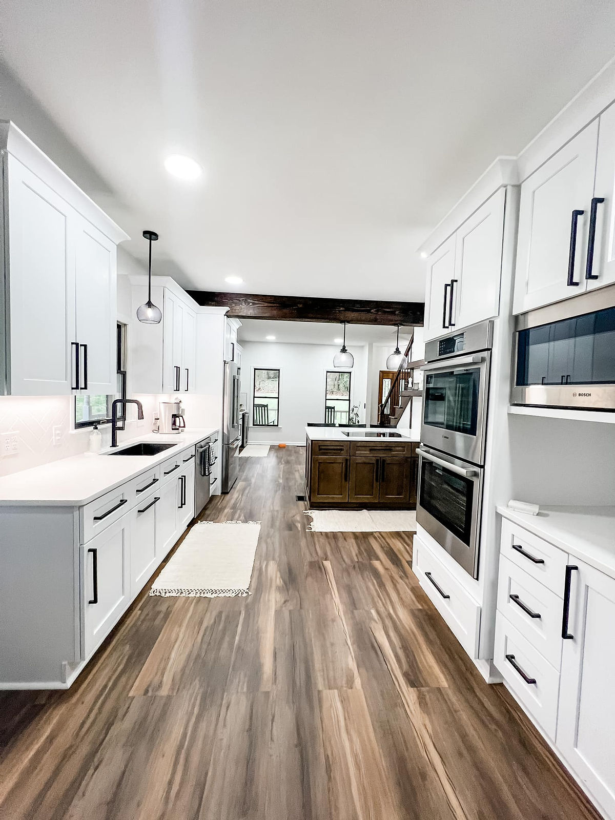 renovated kitchen with wood floors, white cabinetry, counters, and stainless appliances