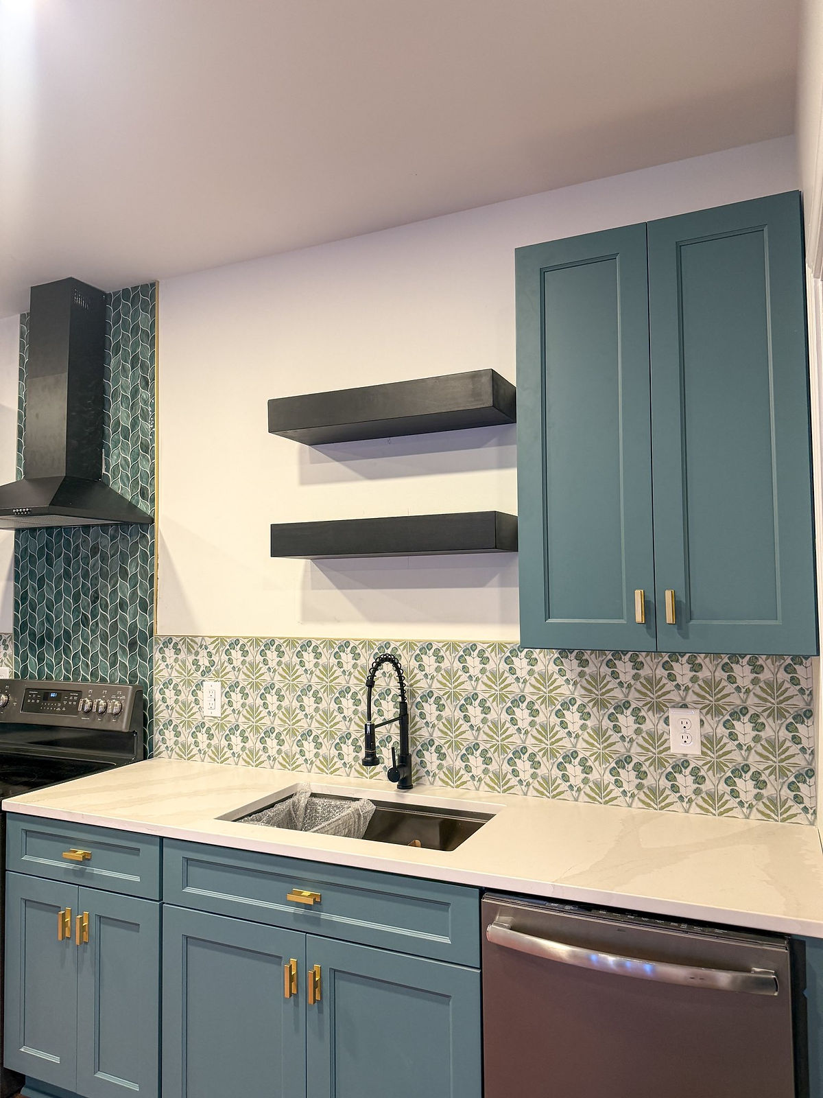 home addition near Huntersville, NC featuring new kitchen with teal cabinetry and coordinating tile backsplash and rand hood surround. gold hardware pops against all the blue
