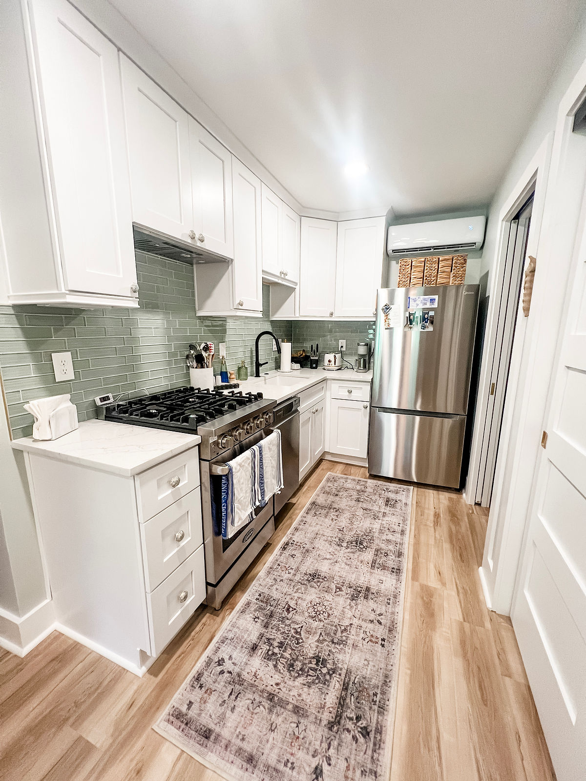 minimalist style kitchen home remodel near Huntersville, NC featuring white cabinetry, stainless appliances, and glass tile backsplash