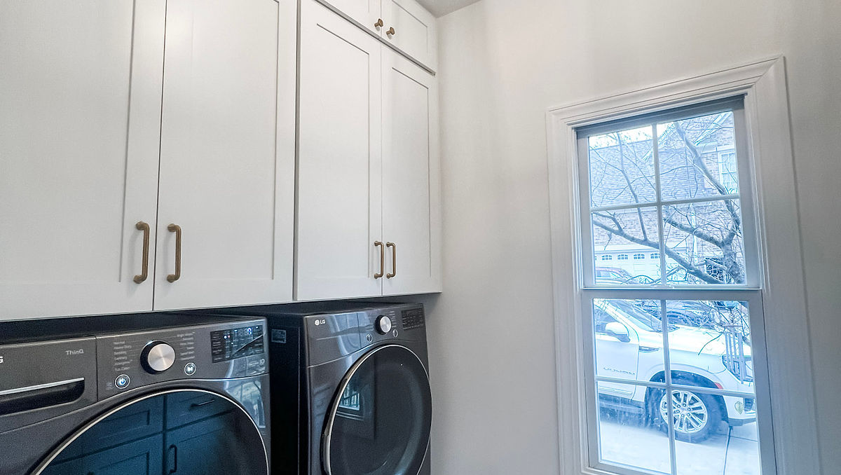home renovation near Huntersville, NC featuring a renovated mudroom/laundry room with white built in cabinetry marble tile floor and farmhouse style light fixture.