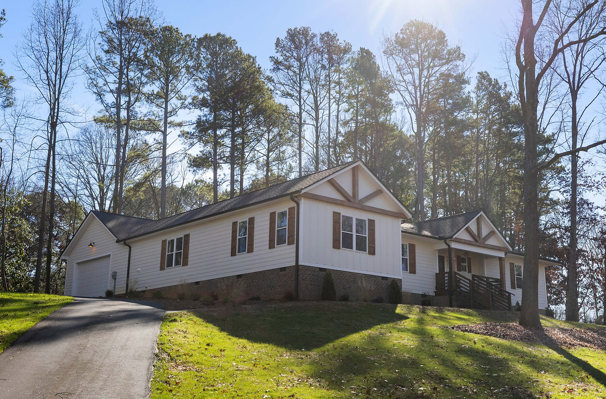 exterior of white house on a hill with farmhouse shutters and decorative beams. home renovation near Huntersville, NC