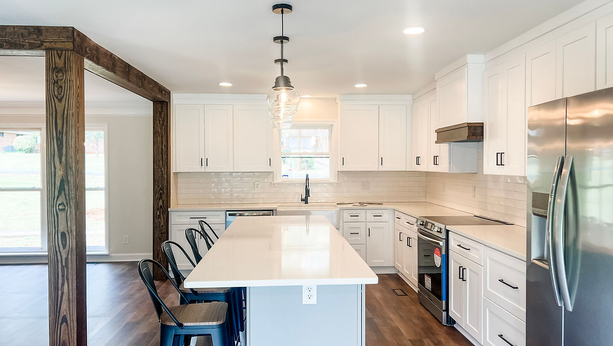 home renovation near Huntersville, NC featuring a bright white kitchen with hardwood floors, and vintage look light fixtures hanging over the island.