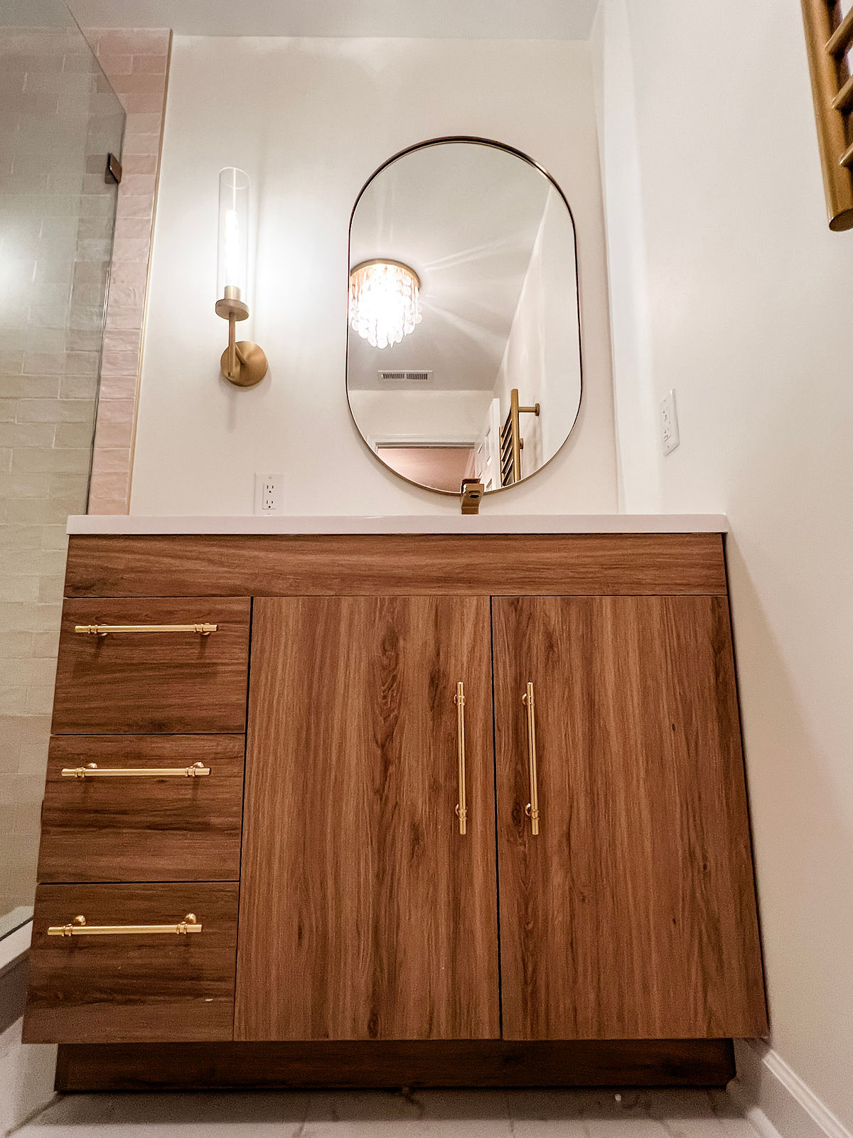 home renovation near Huntersville, NC featuring new bathroom with sleek wooden vanity with gold hardware.