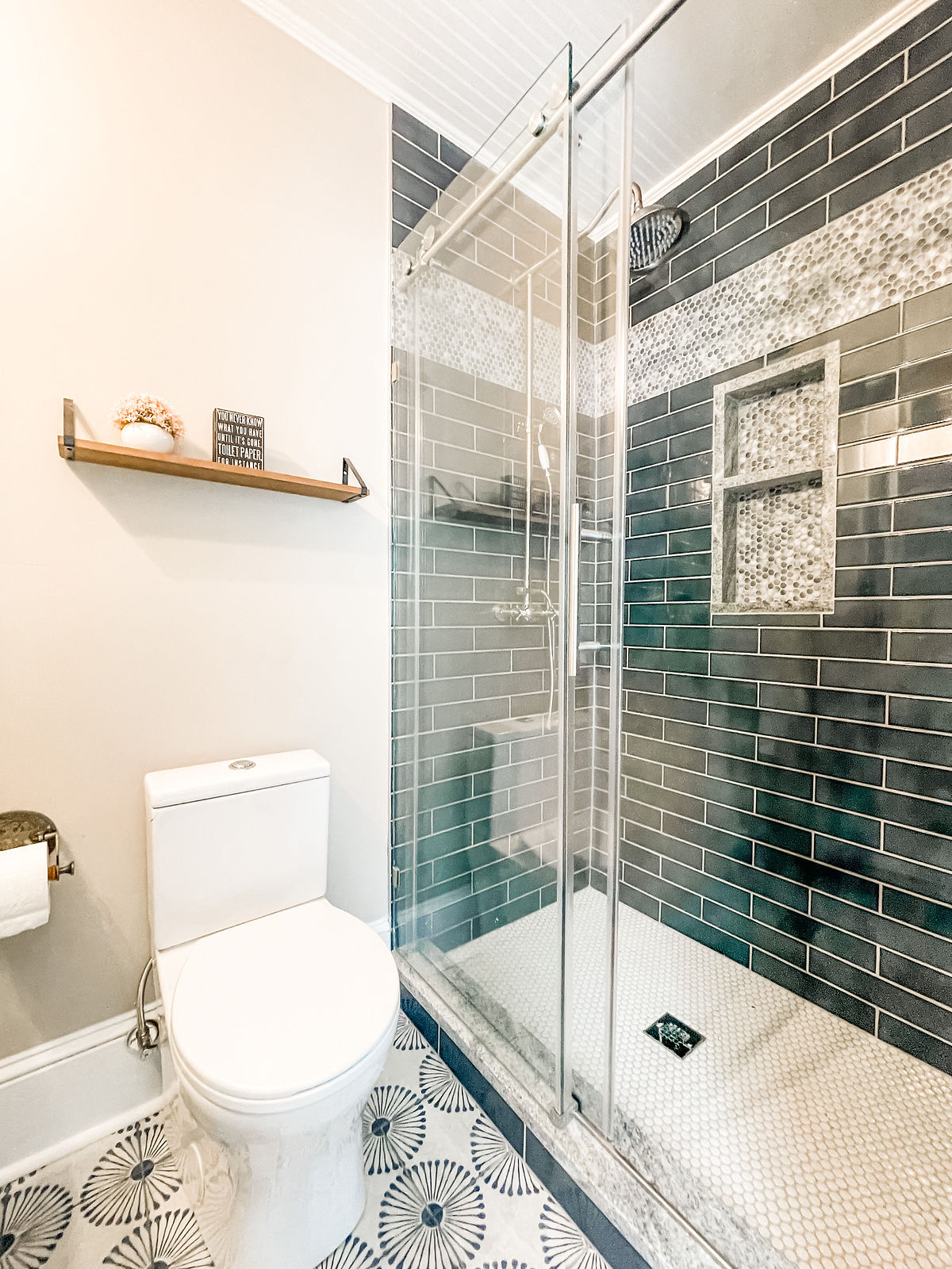 renovated bathroom with dark tiled shower and decorative floor tile