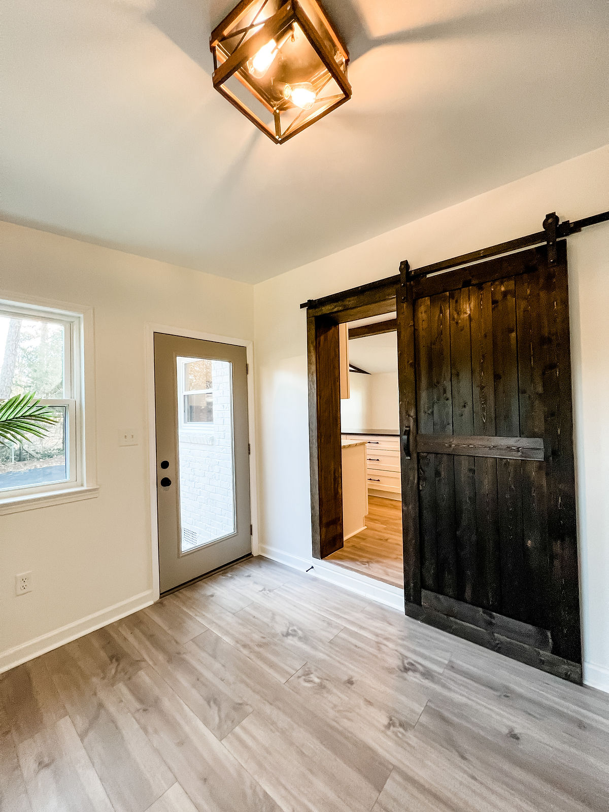 renovated entryway with hardwood floors and sliding barn door into the adjacent space