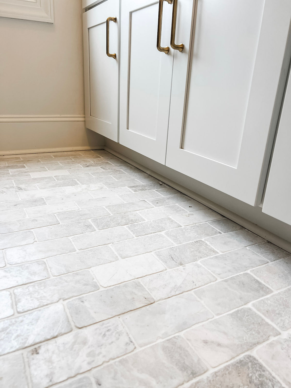 home renovation near Davidson, NC featuring an open laundry/mud room with natural tile floors and light gray cabinetry.