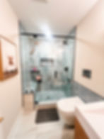 renovated bathroom with gray tiled shower with stone flooring, modern toilet and sink design