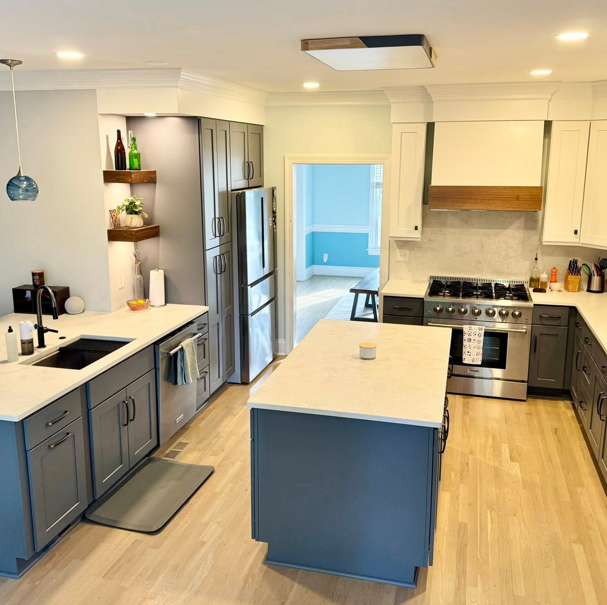 renovated kitchen with light hardwood flooring, dark cabinetry, and white stone counters