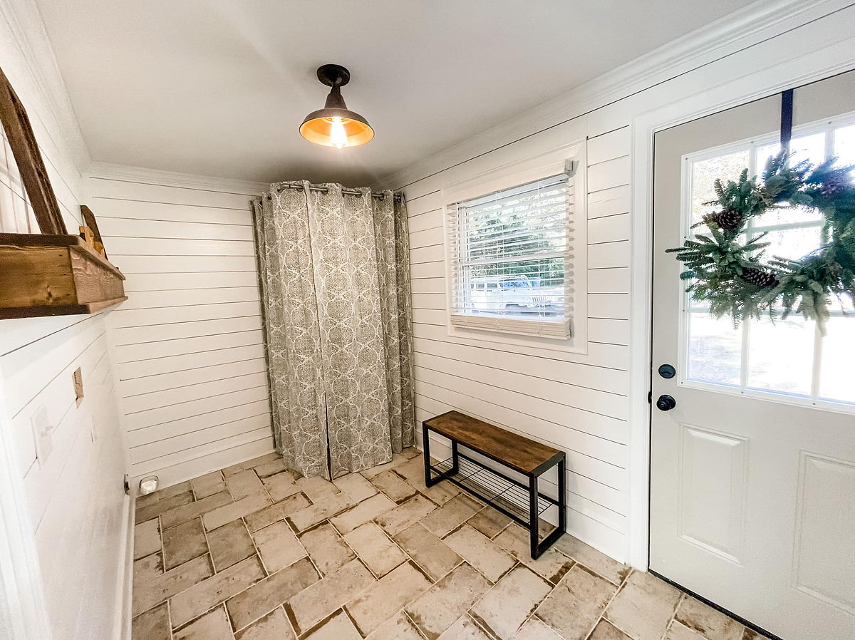 renovated entryway with tile flooring, dark wood bench beneath a window