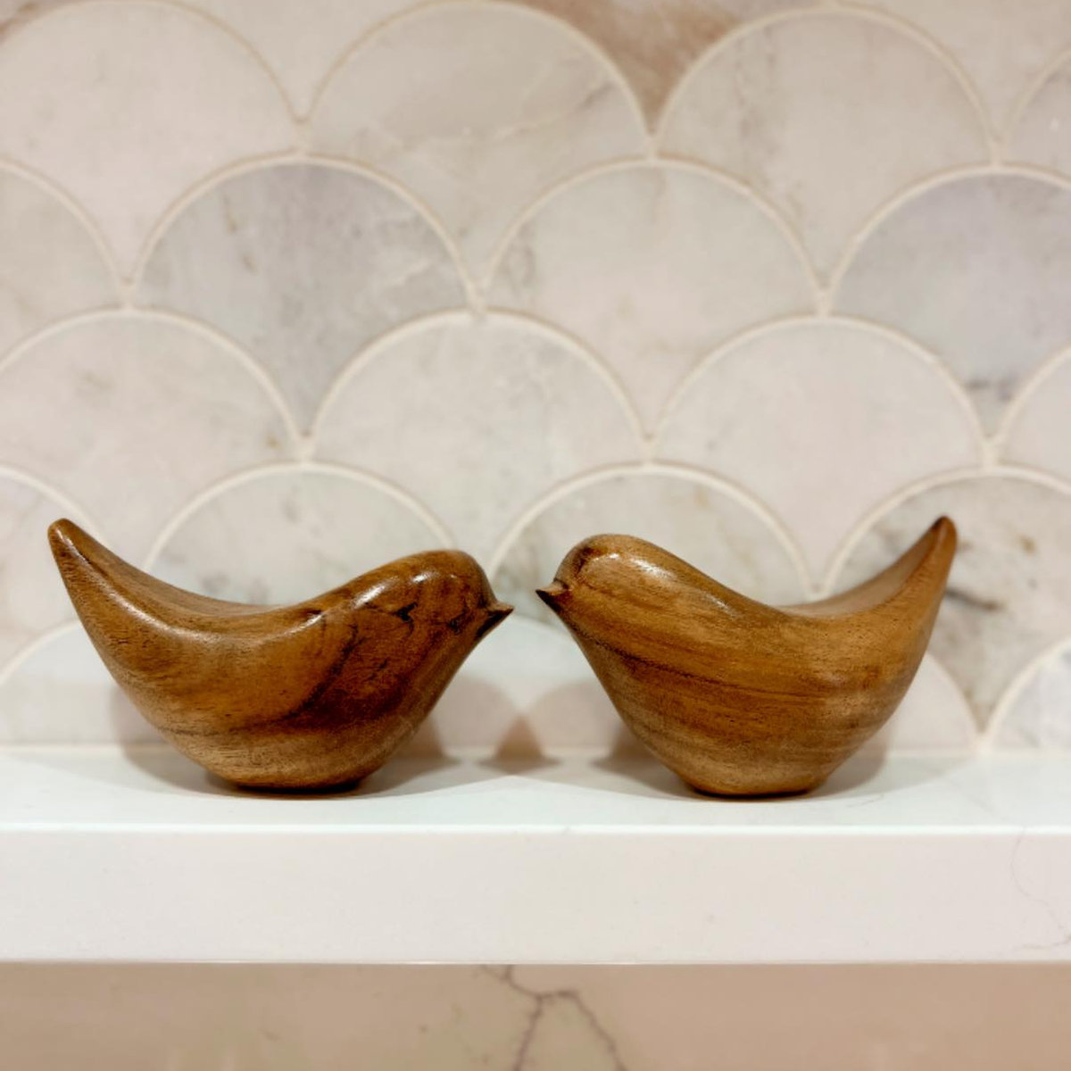 close up on decorative scale style backsplash with wooden bird figurines on a white shelf