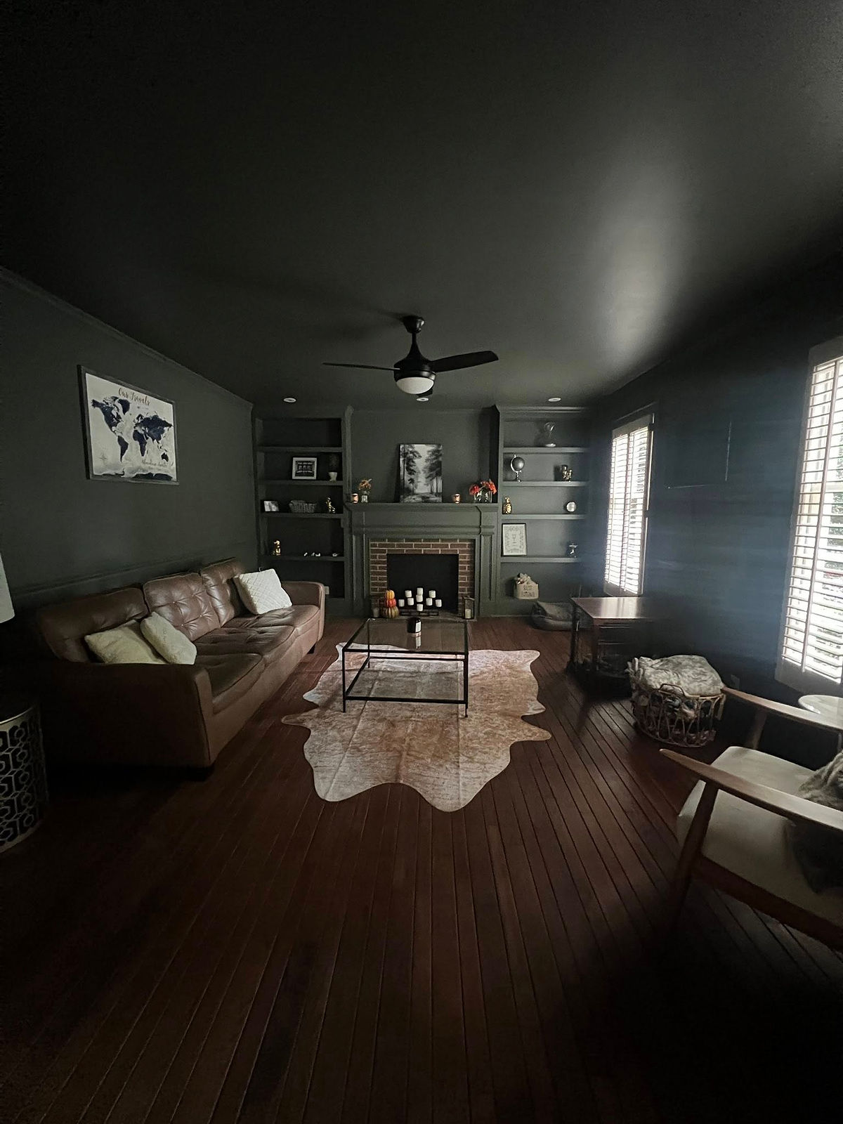 home renovation near Cornelius, NC featuring a color drenched living room in dark green, leather sofa, and faux skin rug on the floor in front of the fireplace.