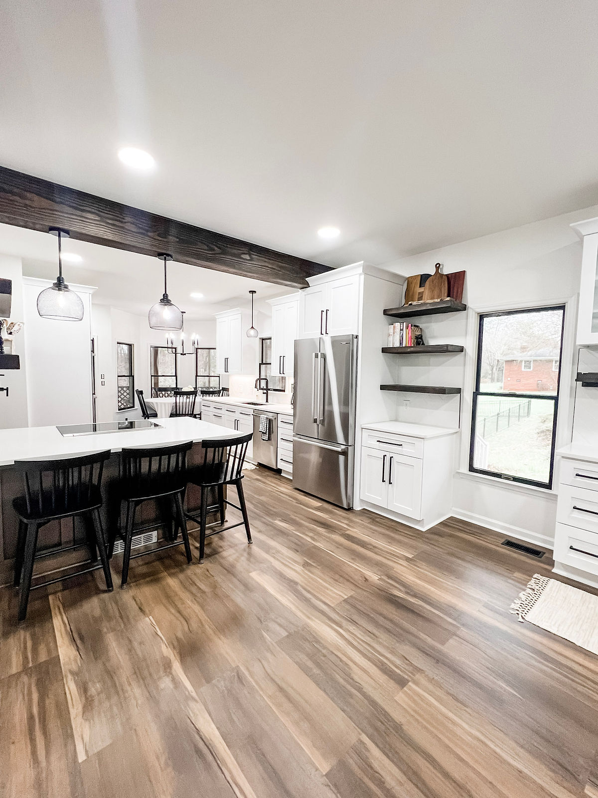 home renovation near Davidson, NC featuring an open concept kitchen/dining space with hardwood floors and white cabinetry.