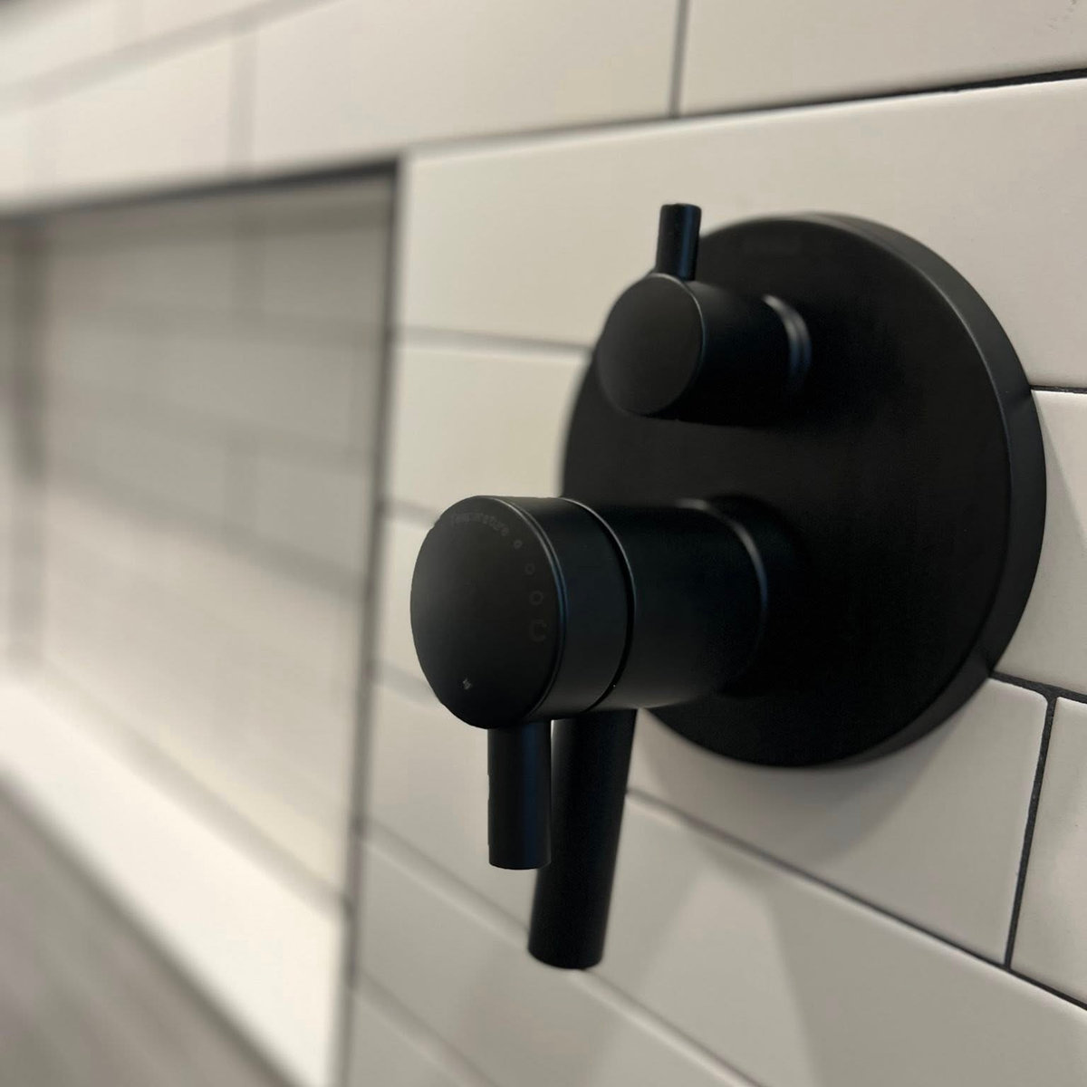 close up on white subway tile with black faucet handle