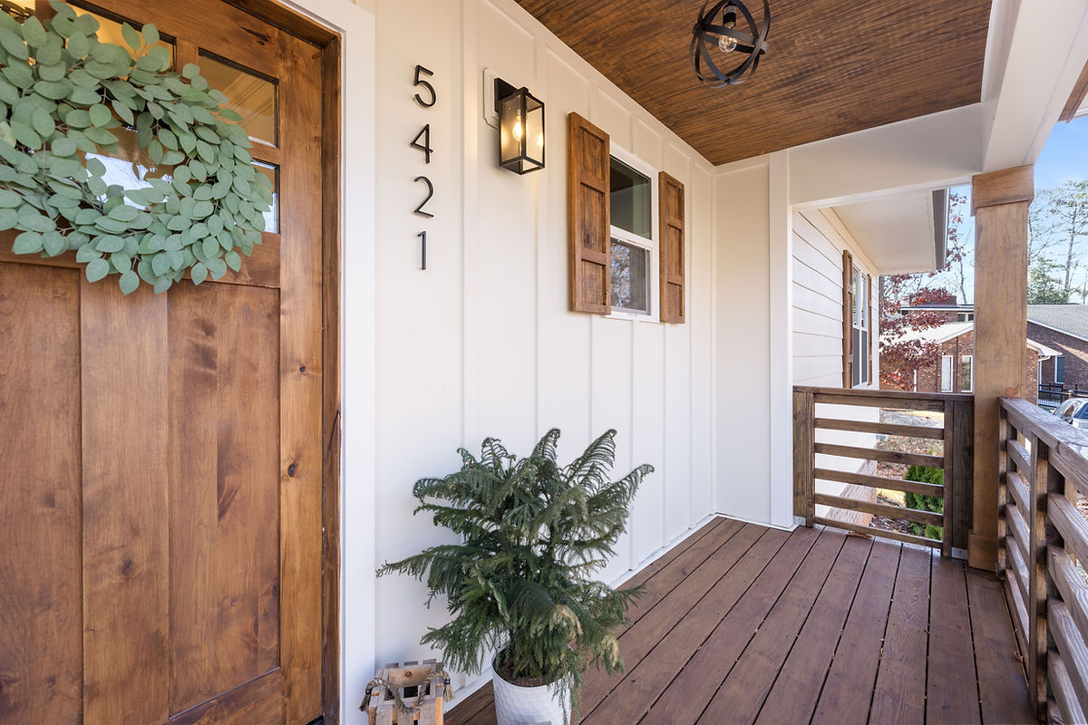 home renovation near Cornelius NC featuring refreshed porch with wooden door and shutters and farmhouse light fixtures