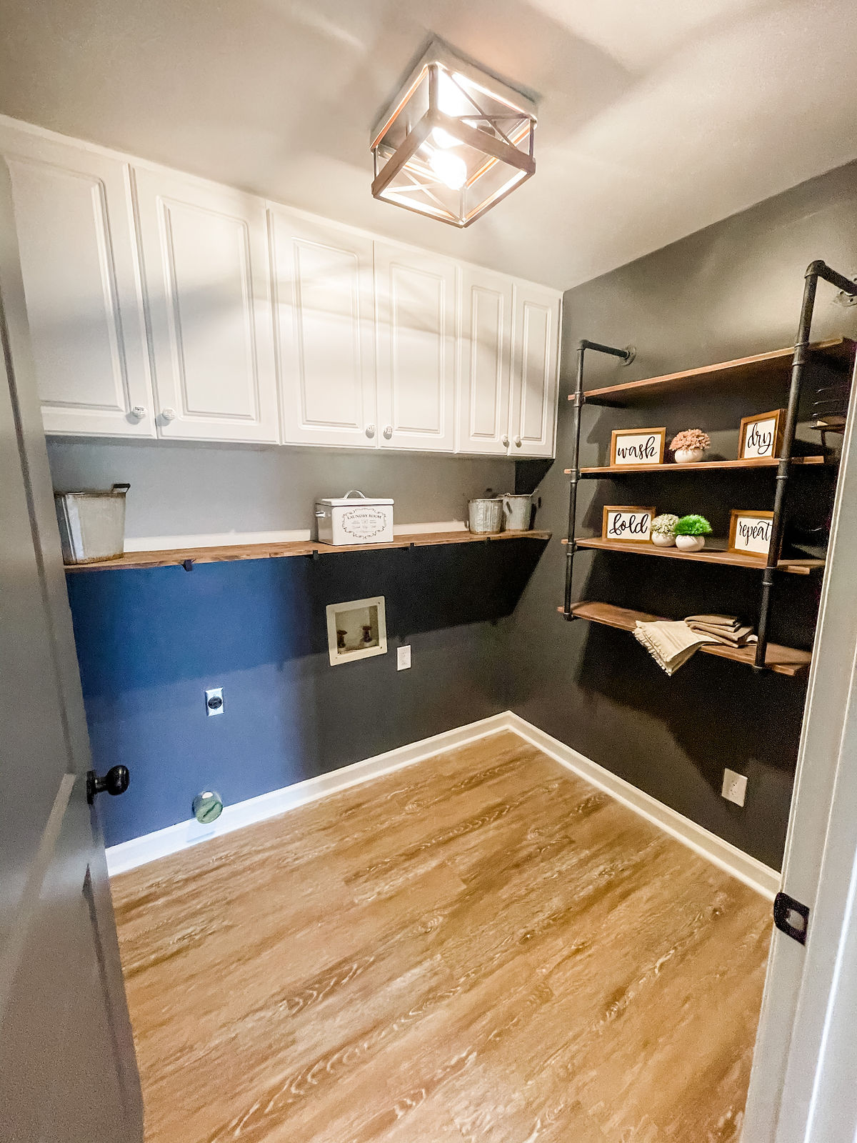 remodeled laundry room with wood floors, gray walls, and industrial style shelving