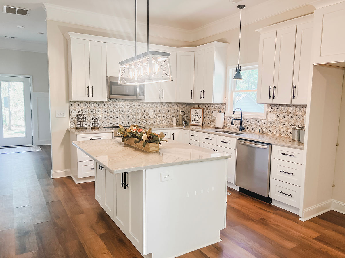 home remodel near Davidson, NC featuring renovated kitchen with decorative tile backsplash, wood floors, and white cabinetry.