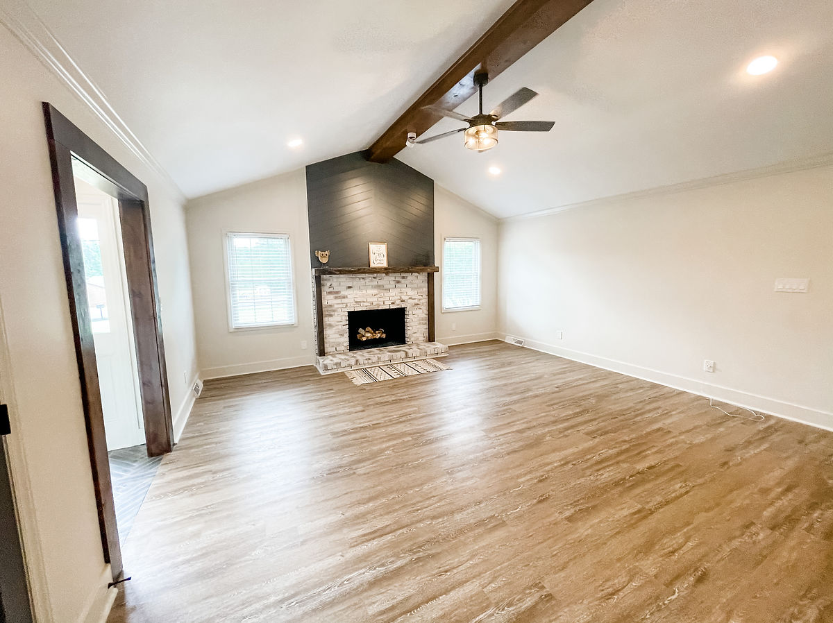 renovated living room with brick fireplace and exposed beam
