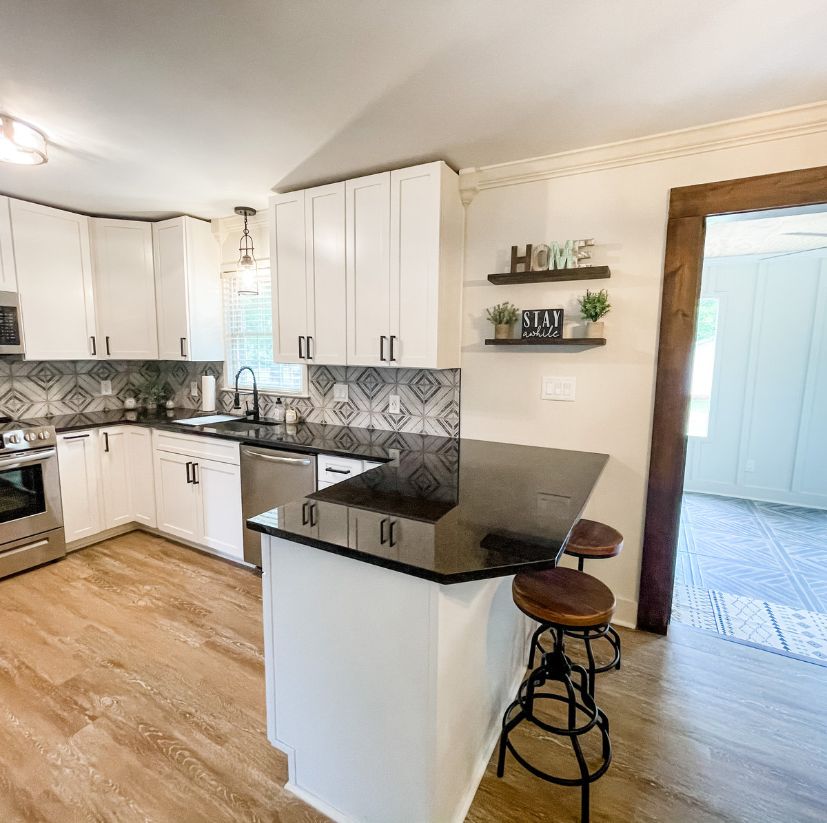 renovated kitchen with black granite countertops, white cabinetry, and decorative tile backsplash