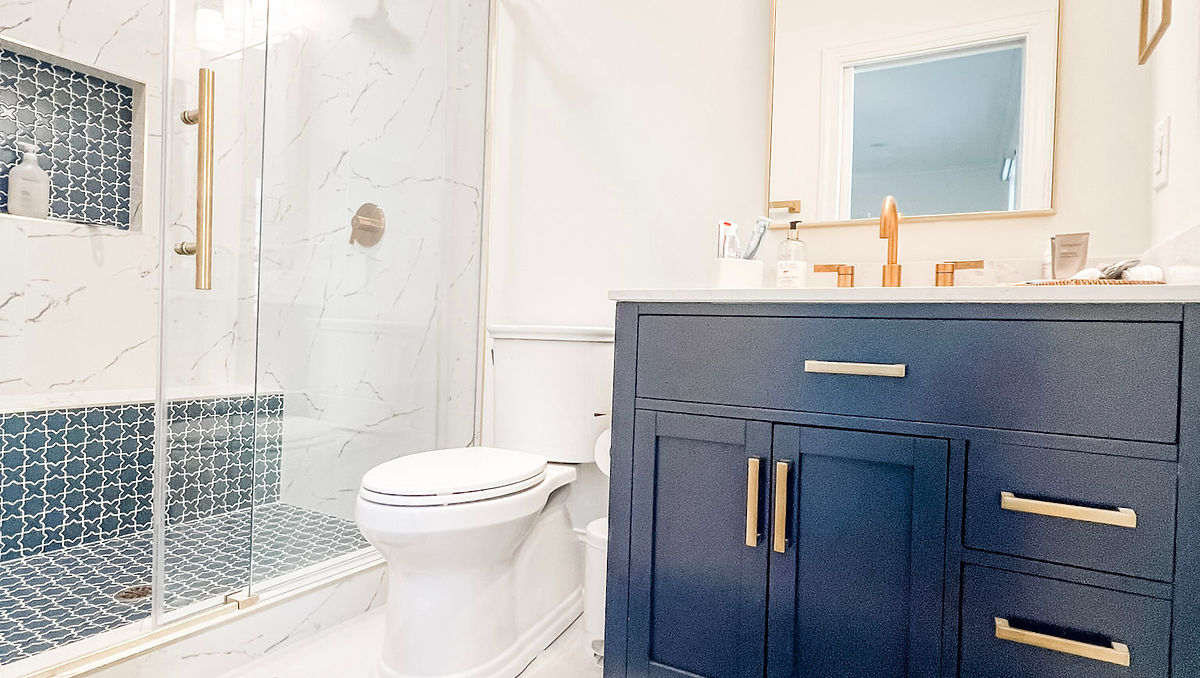 home renovation near Cornelius, NC featuring a bathroom with white tile, marble shower surround, blue vanity, and blue decorative shower flooring tile.