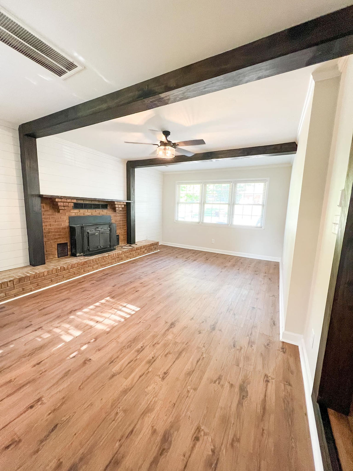 renovated living room with hardwood floors, fresh white paint, and exposed dark wood beams