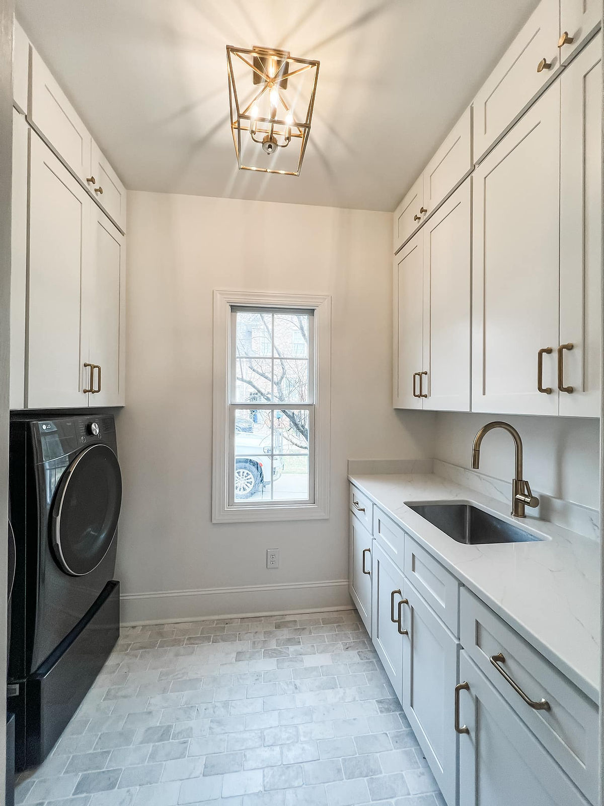 home renovation near Huntersville, NC featuring renovated laundry room with white cabinetry, tile flooring, and a natural counter with sink on the right side.