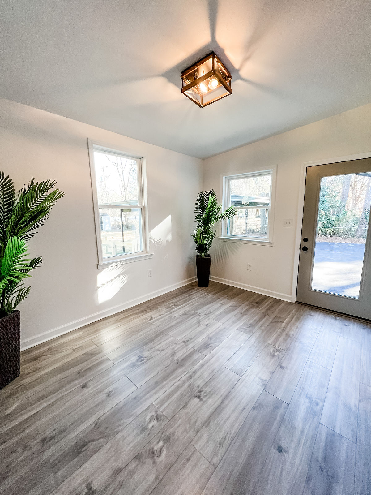 renovated room with fresh white paint, light hardwood floors, and farmhouse light fixture.