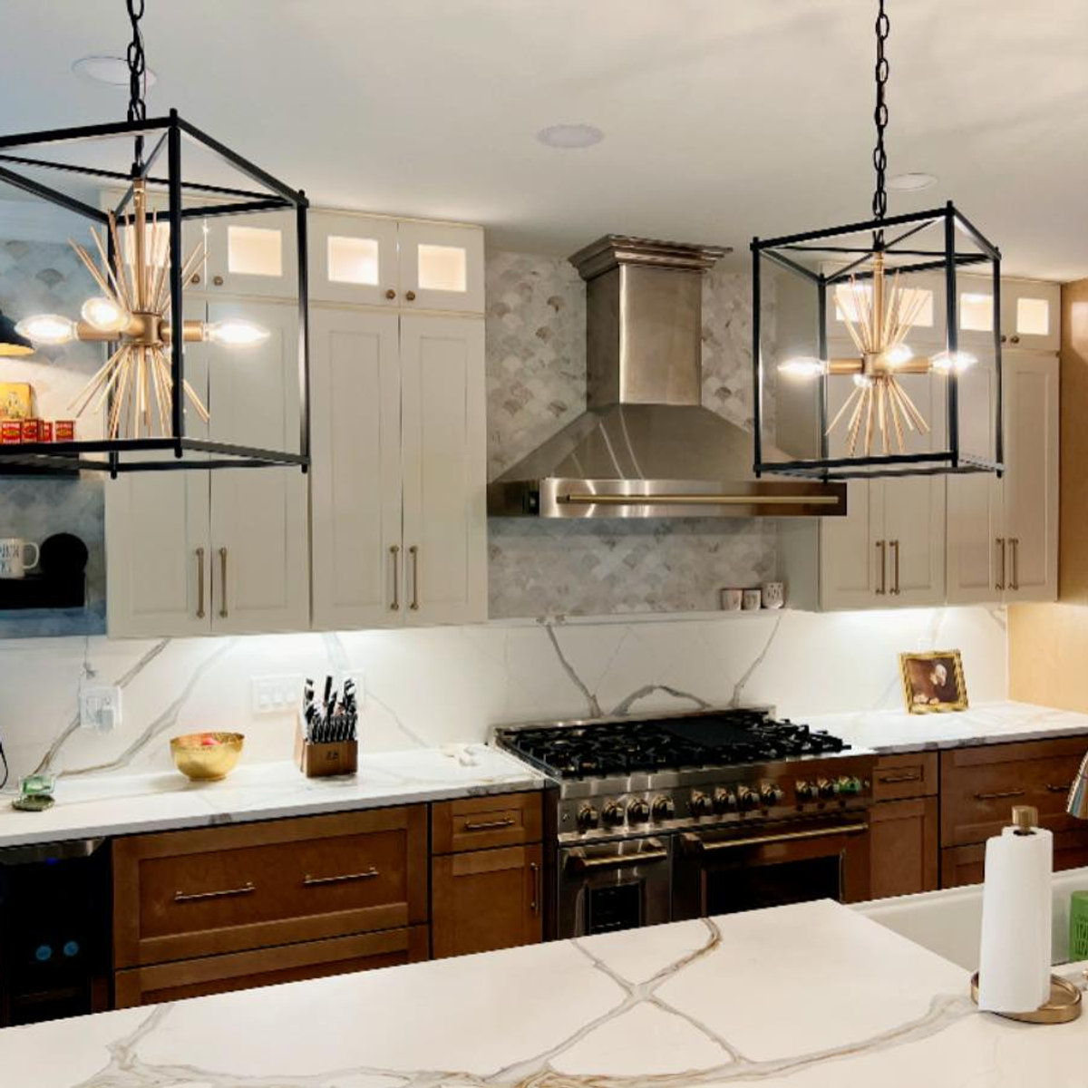 two modern farmhouse pendants hang above  a large kitchen island with bold striated granite counters