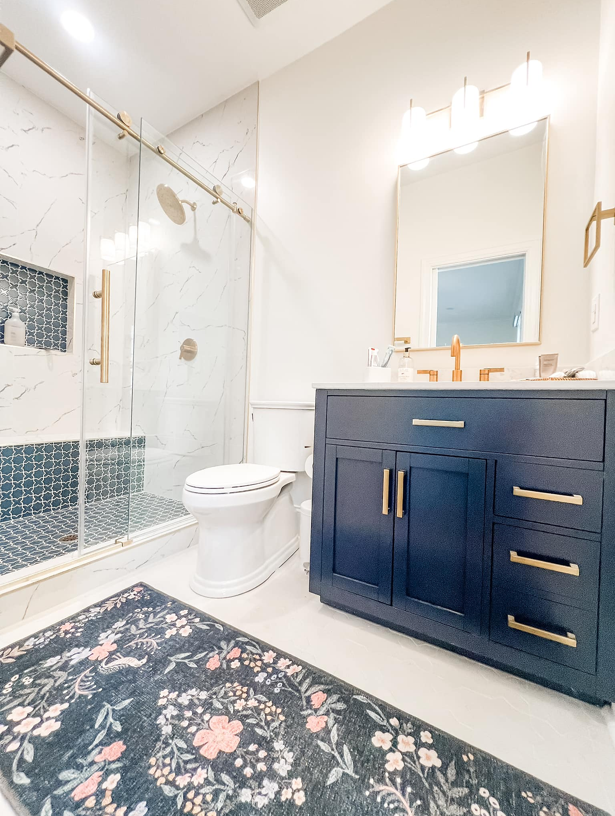 garage conversion completed with full bathroom. Navy vanity with brass hardware, light tiled floor and marble tiled shower.