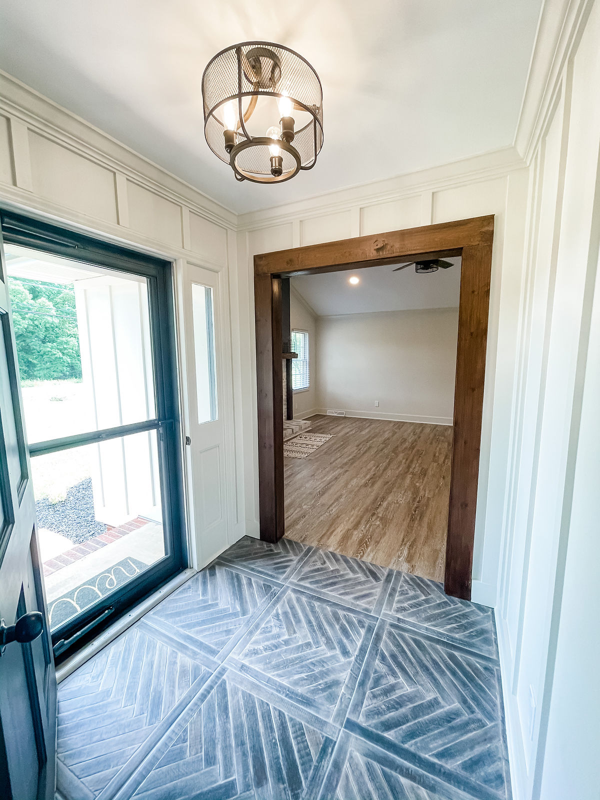 remodeled home with fresh herringbone entryway tile and farmhouse light fixture