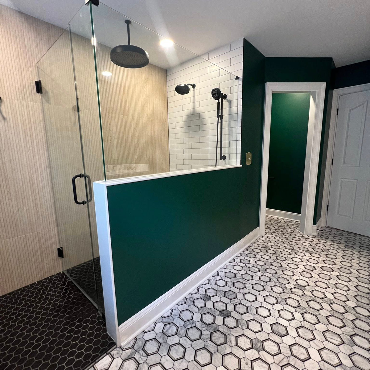 dark green halfwall outside a glass shower enclosure with white trim