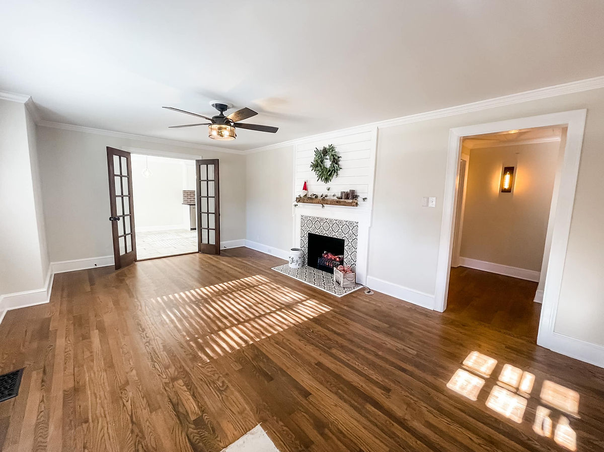 renovated living room with hardwood floors, tiled fireplace, and fresh light paint