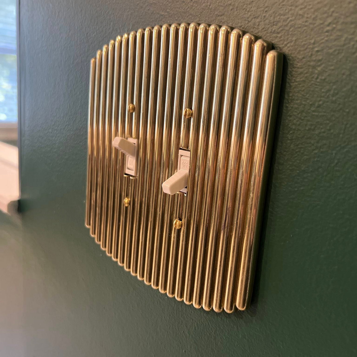 dark green wall with gold retro styled light switch plate