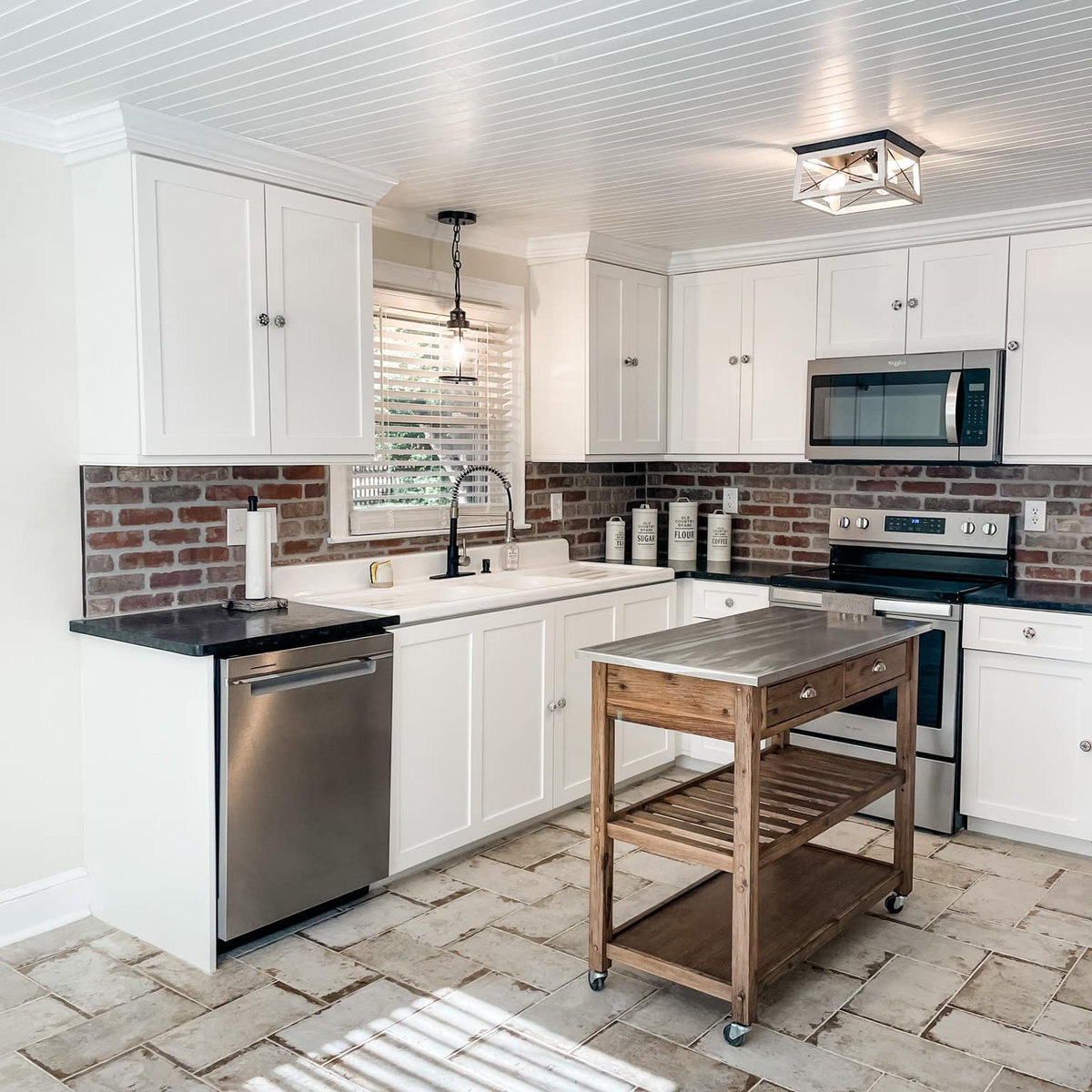 renovation of a small kitchen featuring gray tile flooring, white cabinetry and stainless appliances.