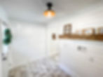 remodeled laundry room with tile floor and white shiplap walls. A rustic wooden shelves show farmhouse style signs: "wash, dry, fold"