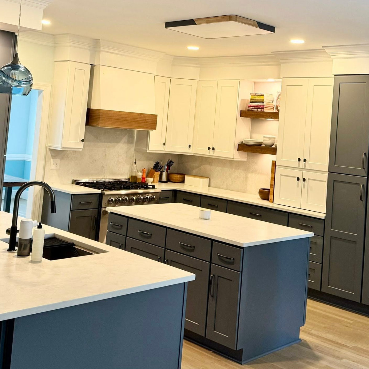 renovated kitchen with dark blue cabinetry, white stone counters, and black hardware