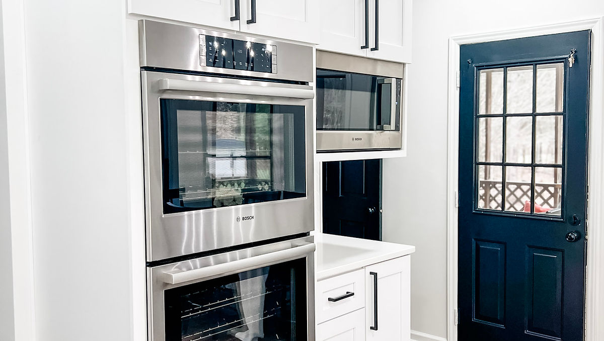 home renovation near Huntersville, NC featuring bright white kitchen with stainless steel double oven and microwave.