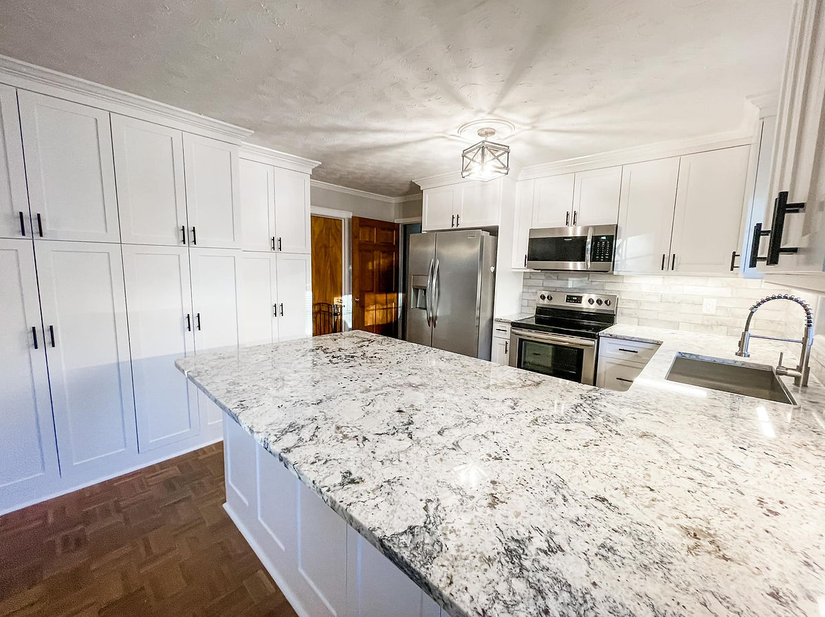 home renovation near Cornelius. NC featuring a renovated kitchen with stone counters, white cabinetry, and stainless steel appliances.