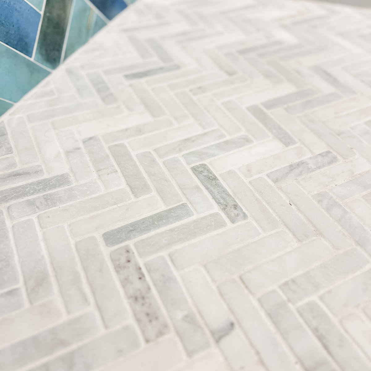 marble herringbone tile, meets a varied blue glass tile wall