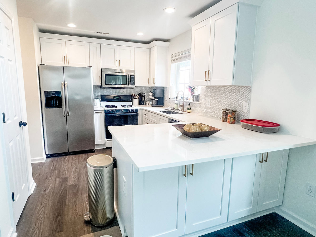 home renovation near Huntersville NC. This kitchen has wood flooring, white counters and cabinets and hidden storage cabinets in the peninsula!